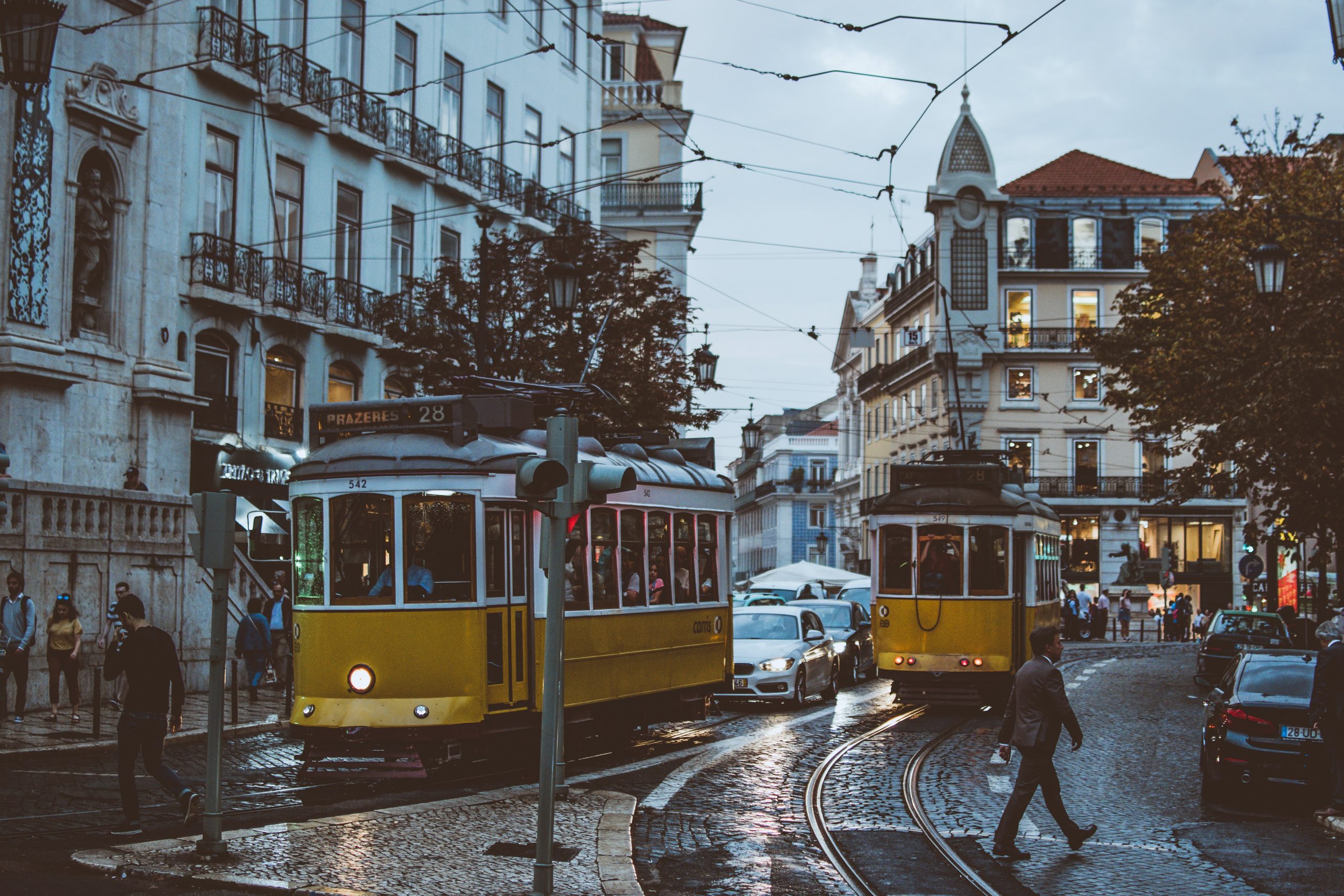 Two yellow trams on a street in Lisbon, known for its Best Coworking Spaces.